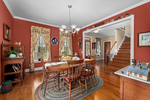 dining space with hardwood / wood-style flooring, a notable chandelier, and ornamental molding