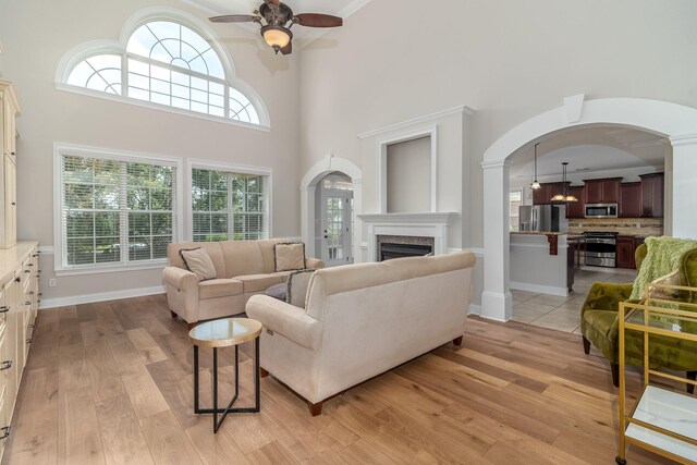 5191 Windmill Pl, Evans, GA 30809 - living area featuring a ceiling fan, light wood finished floors, arched walkways, a fireplace, and a high ceiling