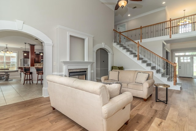 5191 Windmill Pl, Evans, GA 30809 - living room featuring a high ceiling, arched walkways, a chandelier, crown molding, and stairs