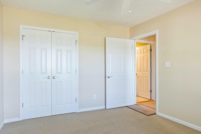 unfurnished bedroom with a closet, baseboards, ceiling fan, and light carpet