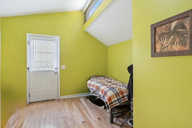 bedroom featuring hardwood / wood-style floors, baseboards, and vaulted ceiling