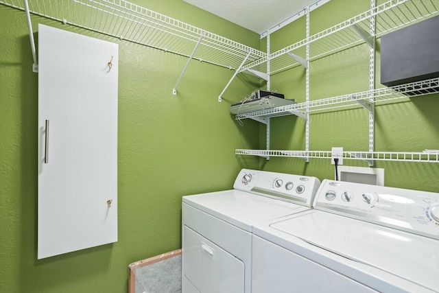 washroom with a textured wall, independent washer and dryer, and laundry area