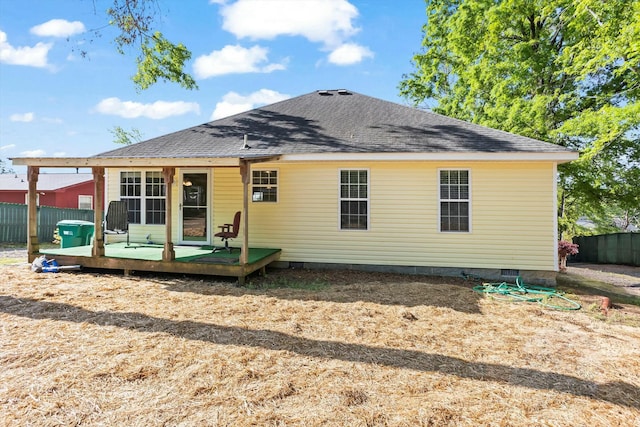 rear view of house featuring a deck, roof with shingles, fence, and crawl space