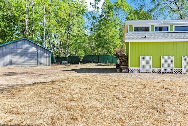 view of yard featuring an outbuilding, a detached garage, fence, and dirt driveway