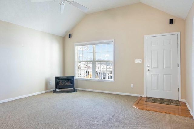 foyer featuring a wood stove, ceiling fan, carpet, and lofted ceiling