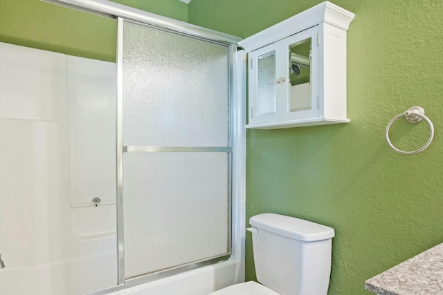 bathroom with a textured wall, toilet, and a shower with door