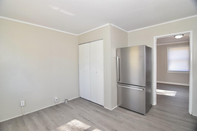 kitchen with stainless steel fridge, crown molding, and light hardwood / wood-style floors