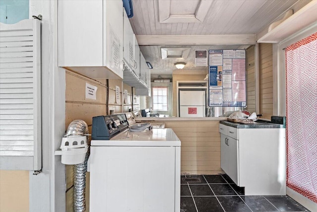 laundry area featuring wooden walls, washer and dryer, and dark tile patterned flooring