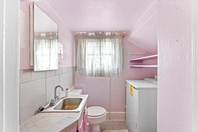 bathroom featuring a textured ceiling, vanity, tile walls, tile patterned flooring, and toilet