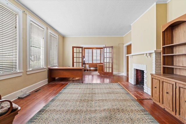 home office with a fireplace, french doors, dark wood-type flooring, and plenty of natural light