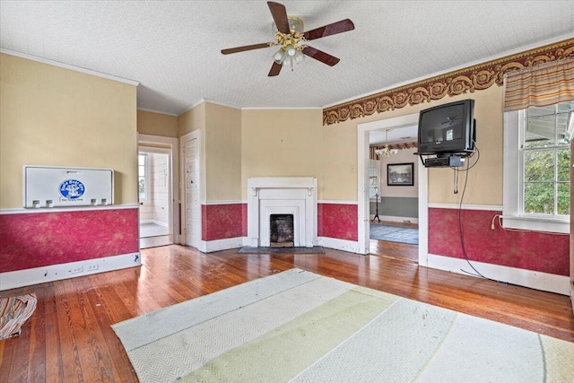 interior space with ceiling fan, crown molding, a textured ceiling, and hardwood / wood-style flooring