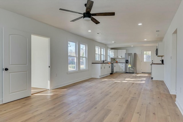 unfurnished living room with light hardwood / wood-style flooring and ceiling fan