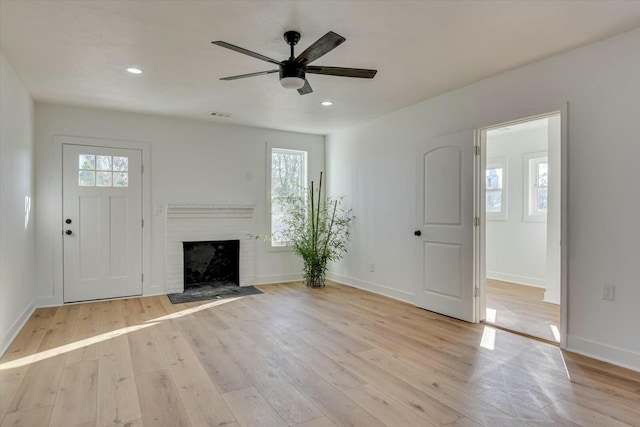 unfurnished living room with a fireplace, light hardwood / wood-style flooring, and ceiling fan