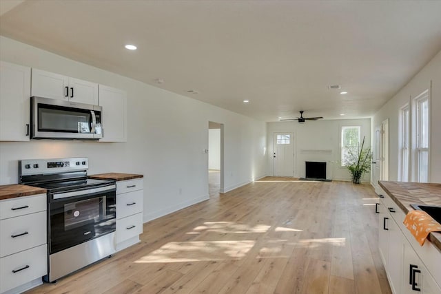 kitchen with butcher block counters, ceiling fan, appliances with stainless steel finishes, white cabinets, and light wood-type flooring