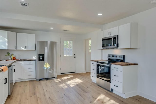 kitchen featuring butcher block counters, white cabinetry, light hardwood / wood-style flooring, and appliances with stainless steel finishes