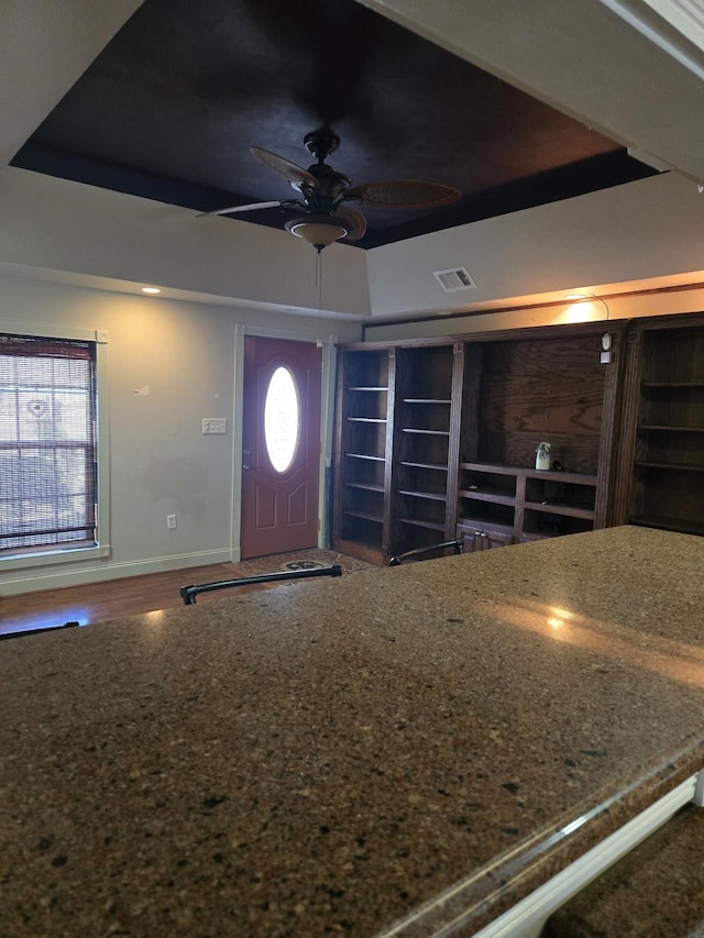 entrance foyer featuring a raised ceiling and ceiling fan