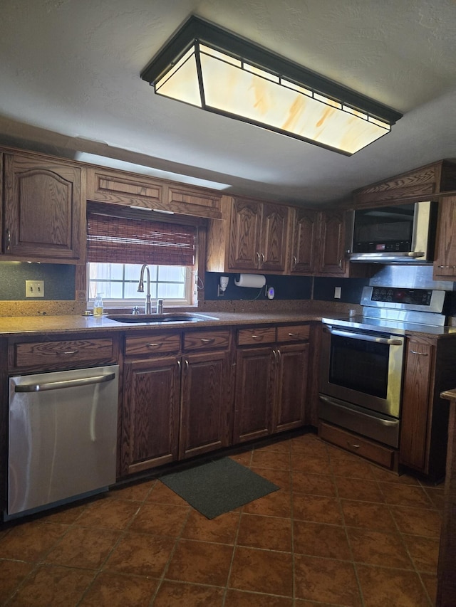 kitchen featuring sink, dark tile patterned floors, dark brown cabinets, and appliances with stainless steel finishes