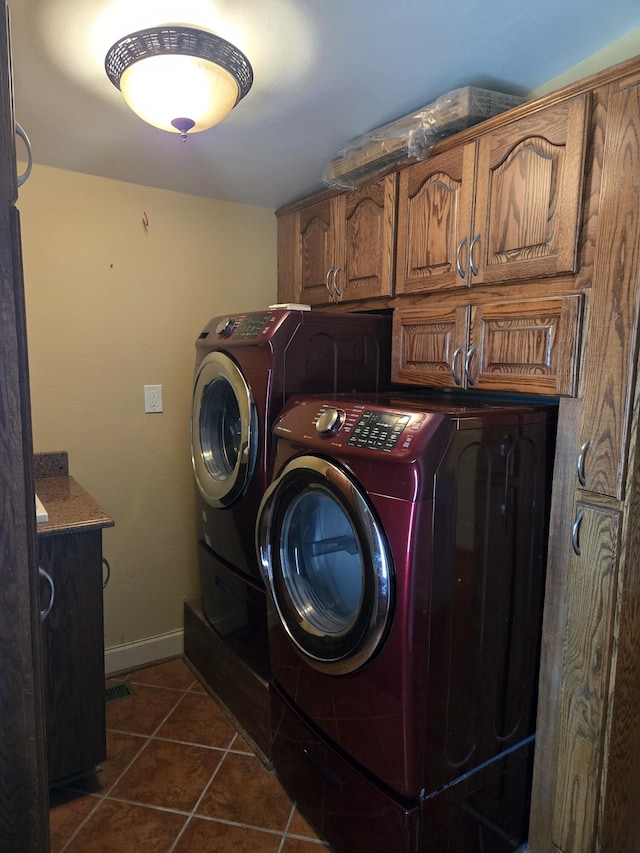 washroom with cabinets, washing machine and clothes dryer, and dark tile patterned floors