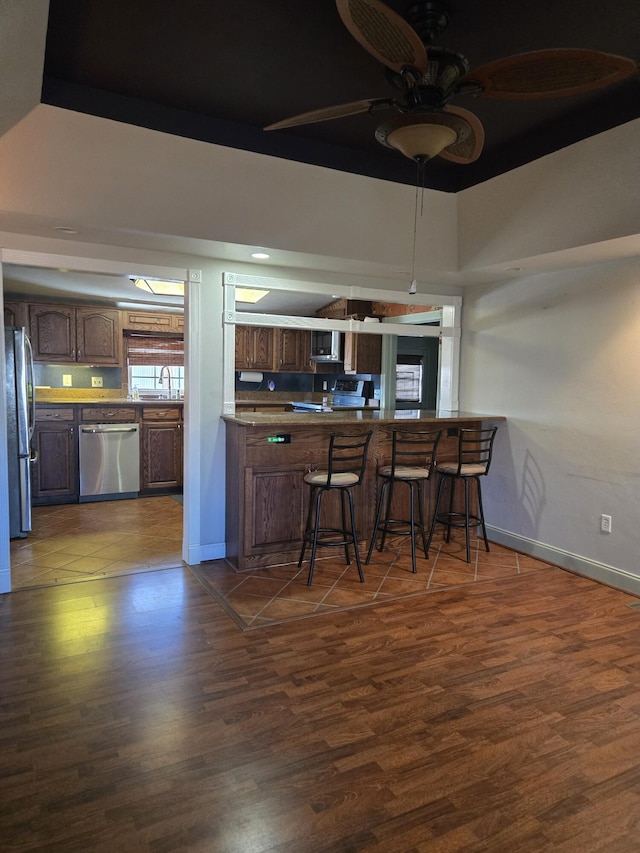 kitchen with a breakfast bar, stainless steel appliances, dark hardwood / wood-style flooring, and kitchen peninsula