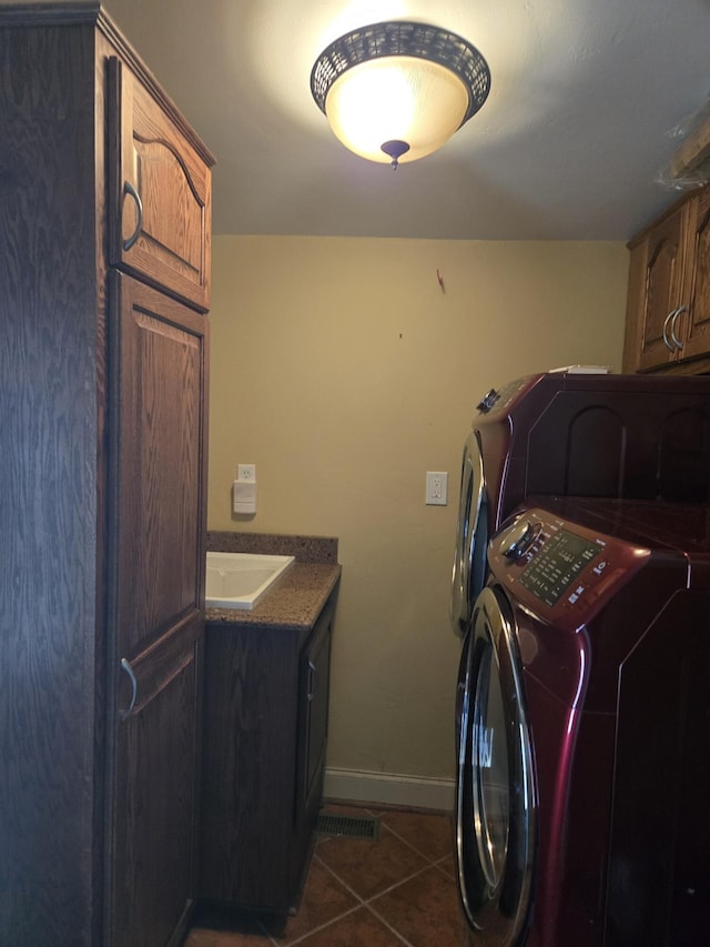 washroom with sink, cabinets, dark tile patterned floors, and washing machine and clothes dryer