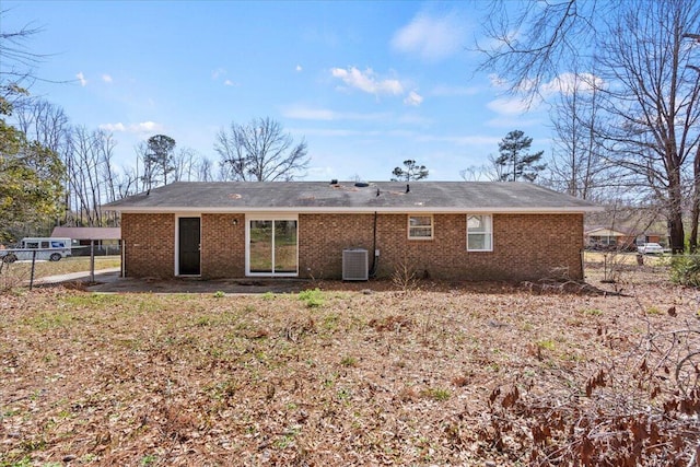 back of property featuring fence, central AC unit, and brick siding