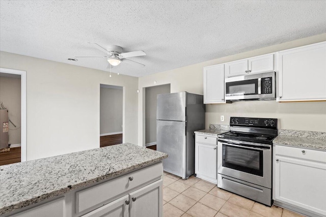 kitchen featuring white cabinets, water heater, light stone counters, and stainless steel appliances