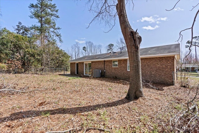 back of house with brick siding, fence, and central air condition unit