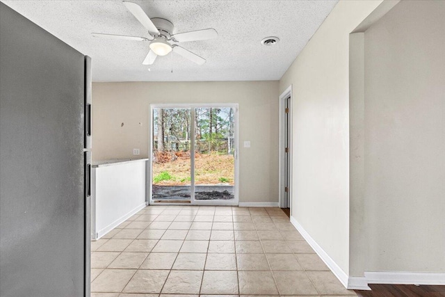 unfurnished room featuring light tile patterned floors, visible vents, baseboards, a ceiling fan, and a textured ceiling