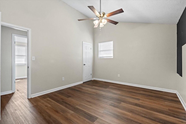 spare room featuring high vaulted ceiling, dark wood-style flooring, a ceiling fan, and baseboards