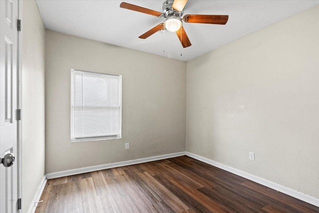 spare room with ceiling fan, baseboards, and dark wood-type flooring