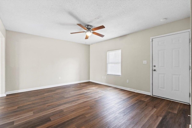 empty room featuring dark wood-style floors, a textured ceiling, a ceiling fan, and baseboards