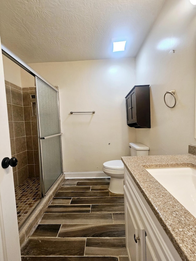4596 Hickory Dr, Evans, GA 30809 - bathroom featuring toilet, a stall shower, wood tiled floor, and a textured ceiling