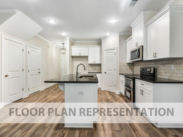 kitchen featuring appliances with stainless steel finishes, a sink, dark countertops, wood finished floors, and a kitchen island with sink