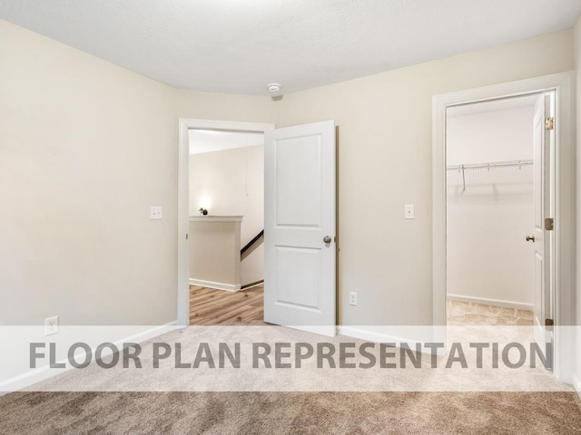 unfurnished bedroom with carpet flooring, a walk in closet, a closet, and baseboards