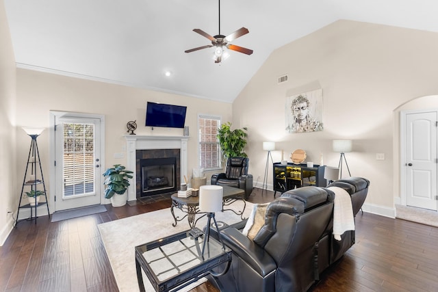 living room featuring ceiling fan, lofted ceiling, dark hardwood / wood-style floors, and a tiled fireplace