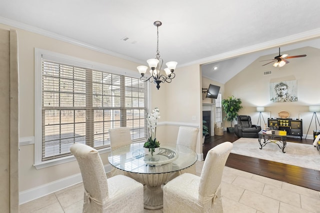 tiled dining room with lofted ceiling, ceiling fan with notable chandelier, and ornamental molding