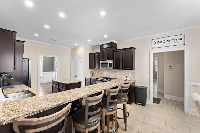 kitchen featuring sink, crown molding, appliances with stainless steel finishes, light stone countertops, and a kitchen island