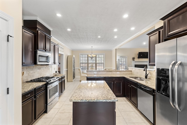 kitchen with sink, appliances with stainless steel finishes, a center island, ornamental molding, and decorative light fixtures