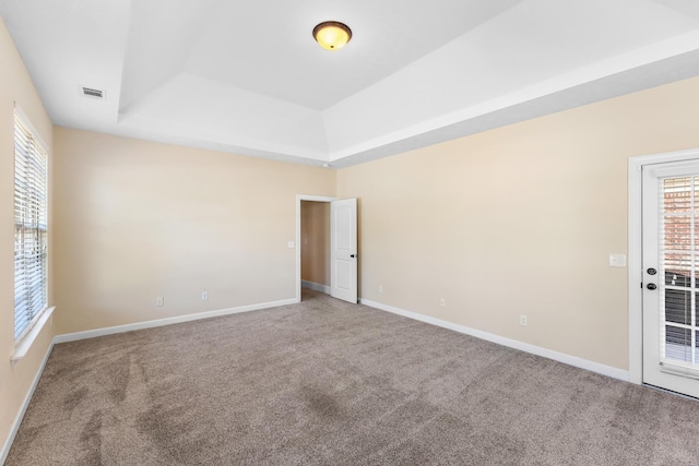 carpeted empty room with a tray ceiling