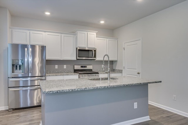 6093 Whitewater Dr, North Augusta, SC 29841 - kitchen with stainless steel appliances, a sink, white cabinets, light wood-style floors, and an island with sink