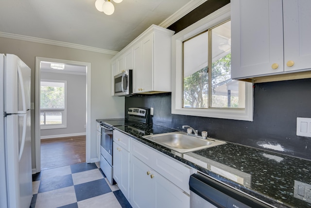 kitchen featuring ornamental molding, a sink, white cabinetry, appliances with stainless steel finishes, and light floors