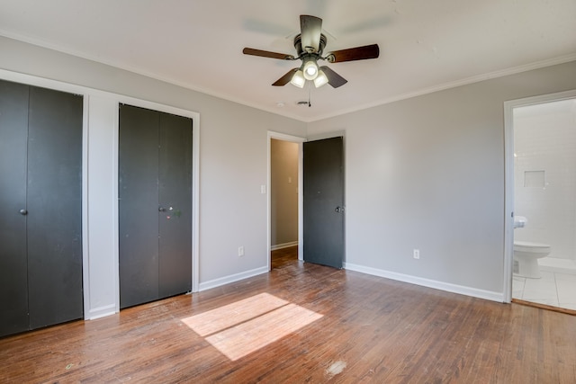 unfurnished bedroom with baseboards, multiple closets, and wood finished floors