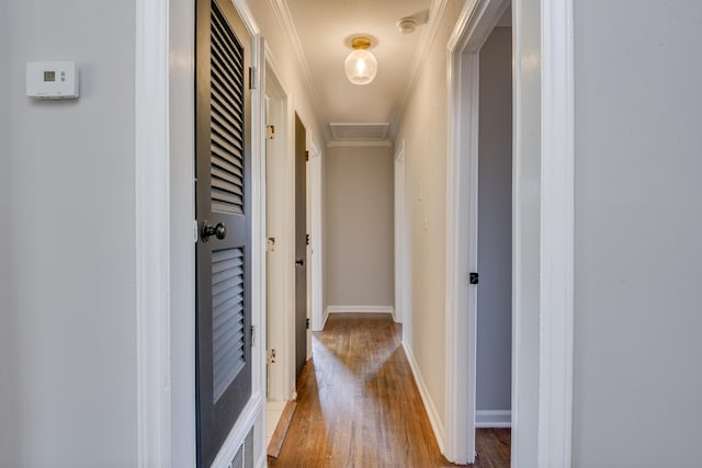 hallway with attic access, crown molding, baseboards, and wood finished floors