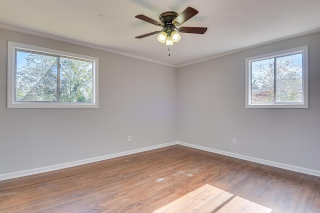 empty room with baseboards, a healthy amount of sunlight, wood finished floors, and ornamental molding