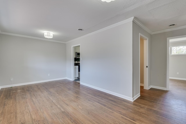 empty room with visible vents, baseboards, wood finished floors, and ornamental molding