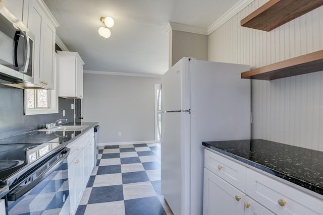 kitchen featuring stainless steel microwave, range with electric stovetop, freestanding refrigerator, crown molding, and dark floors