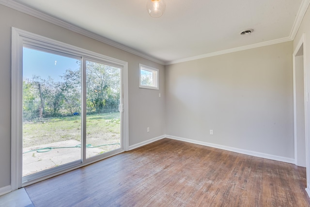 empty room featuring visible vents, crown molding, baseboards, and wood finished floors