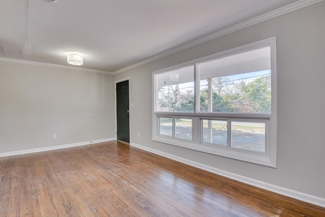 unfurnished room featuring wood finished floors, baseboards, and ornamental molding