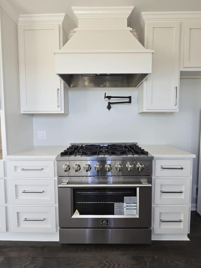 kitchen featuring light countertops, white cabinets, custom range hood, and high end range