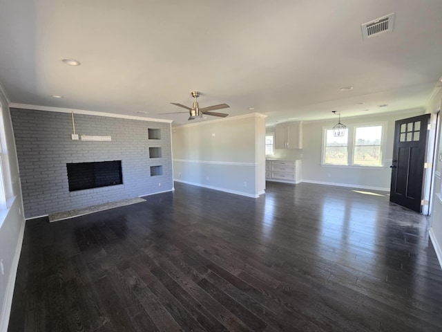 unfurnished living room with dark wood-style floors, visible vents, a fireplace, and a ceiling fan